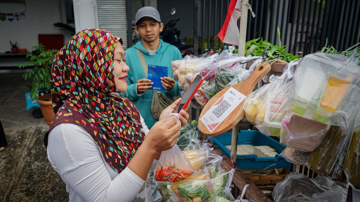 A consumer takes advantage of paying with QRIS digital money when shopping at a mobile vegetable vendor in Malang, November 2022